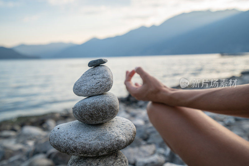 日落时分在湖边的stack rock附近练习瑜伽和冥想的人的细节